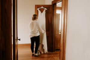 Wedding dress preparation in hallway with wooden trim.