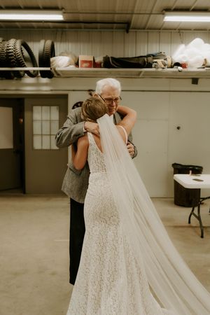 Wedding dress preparations showing intricate lace details and flowing train in a basement venue.