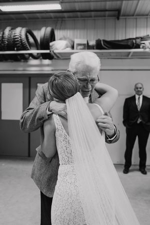 Black and white photo of a wedding dress being adjusted in a basement setting.
