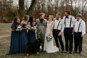 Wedding party in navy and white attire gathered for photos in a winter landscape.
