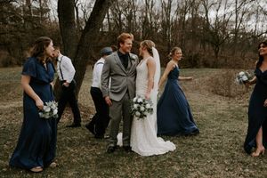 Wedding party members laugh together during outdoor photo session in winter setting.