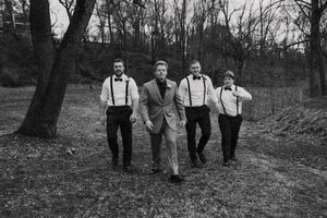Wedding party walks together through a wooded area in black and white photography.