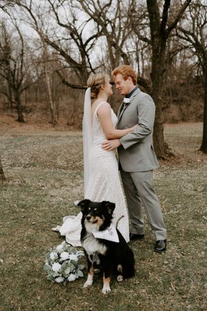 Couple poses with their black and white dog during outdoor wedding photos.