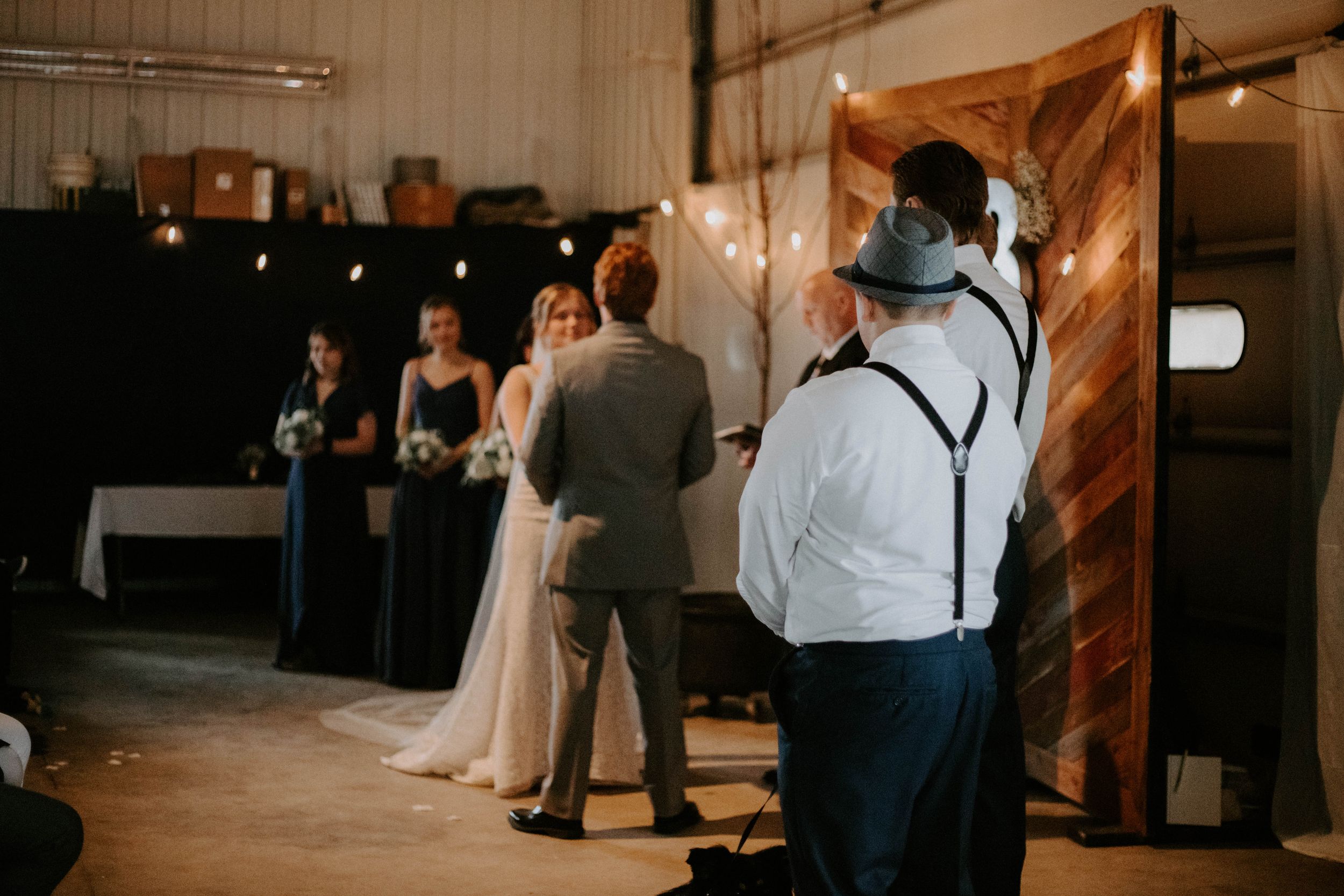 Wedding guests seated in rows at an indoor ceremony with warm lighting and rustic wooden decor.