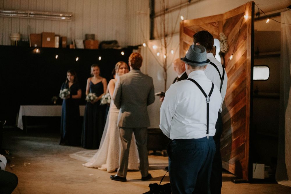 Wedding guests seated in rows at an indoor ceremony with warm lighting and rustic wooden decor.