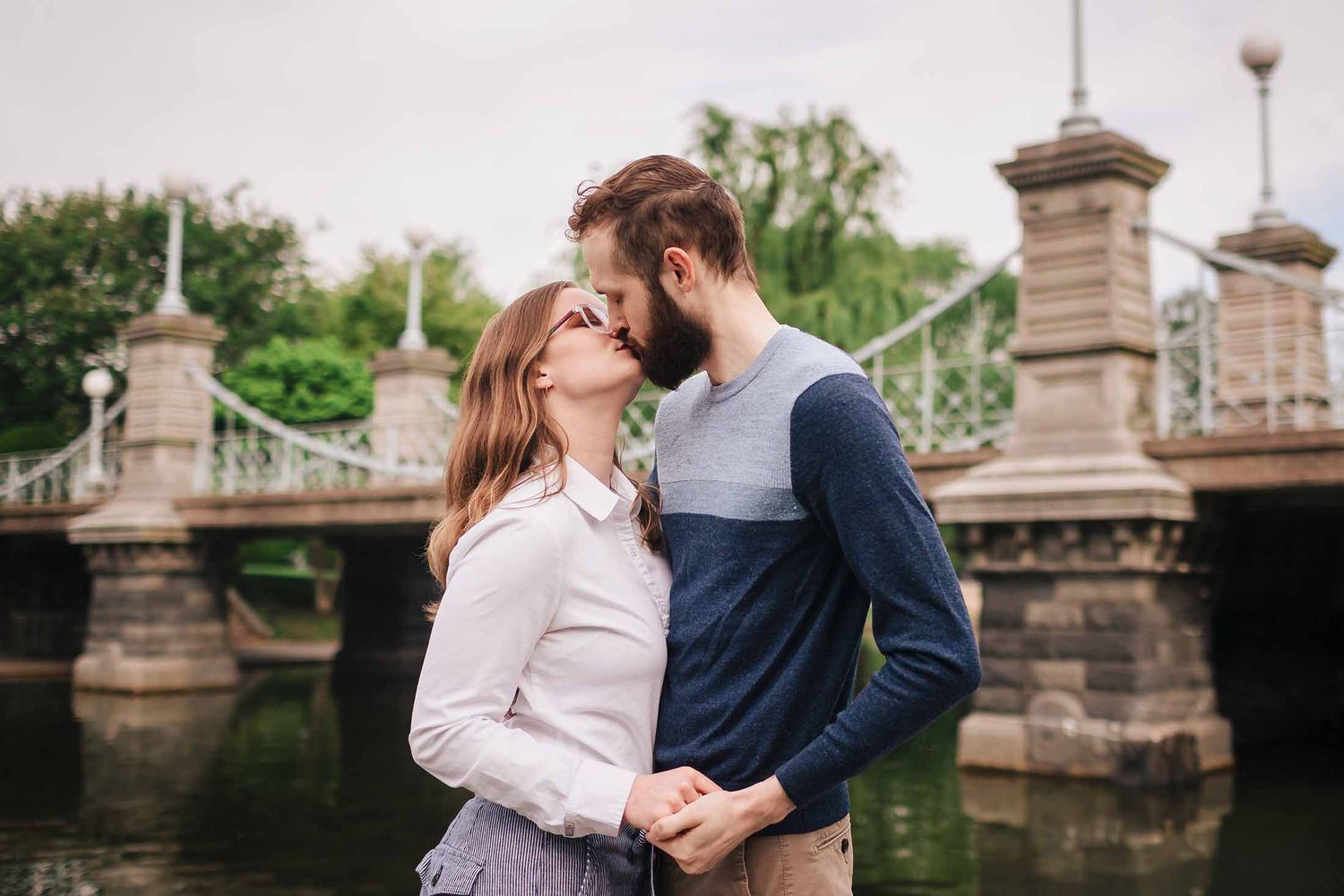 Sweet kiss shared by couple beside historic Boston Public Garden Foot Bridge during engagement photos