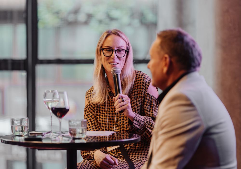 Business professionals having wine and conversation at a restaurant table with wine glasses.
