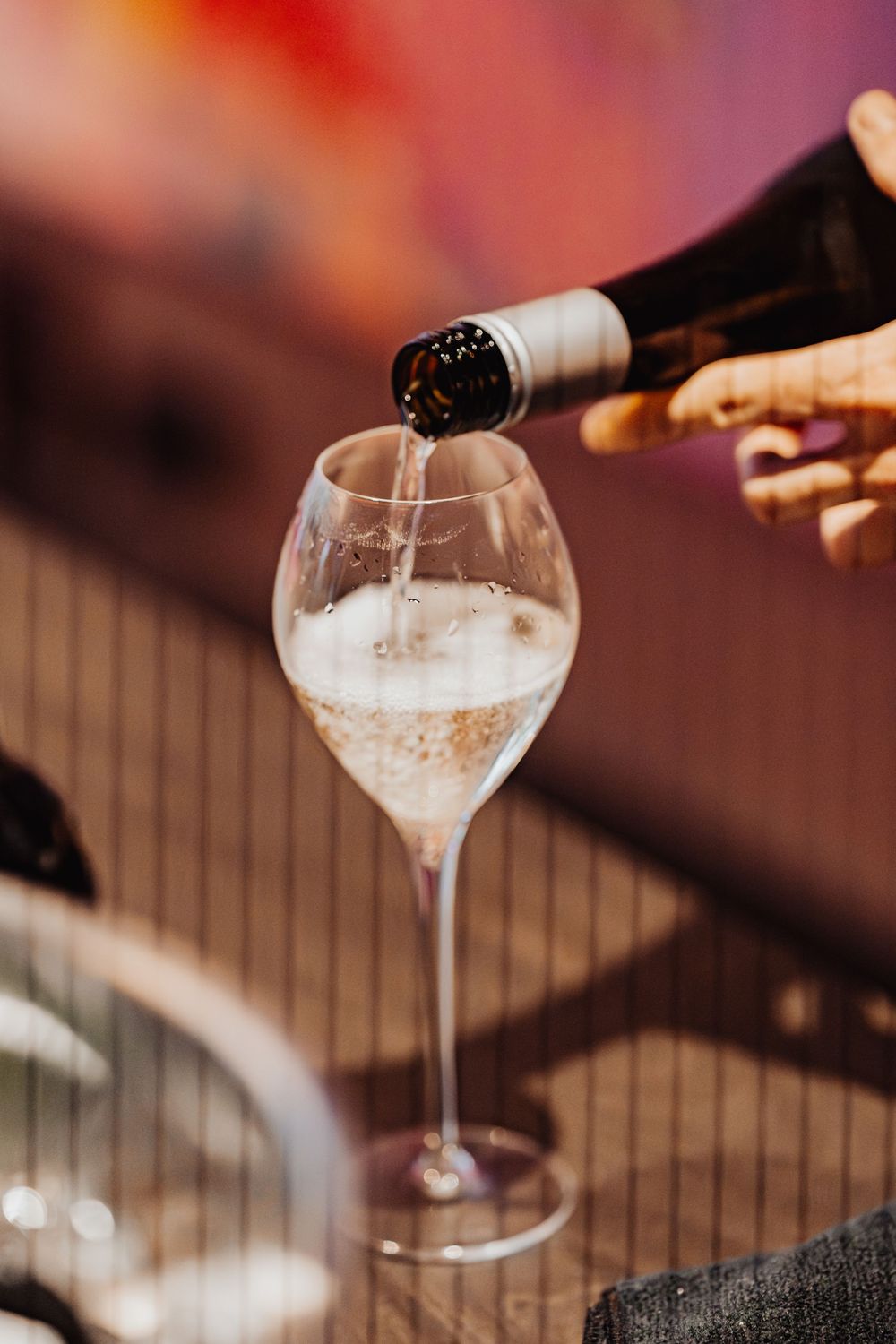 Champagne being poured into an elegant wine glass with bubbles rising in warm ambient lighting.