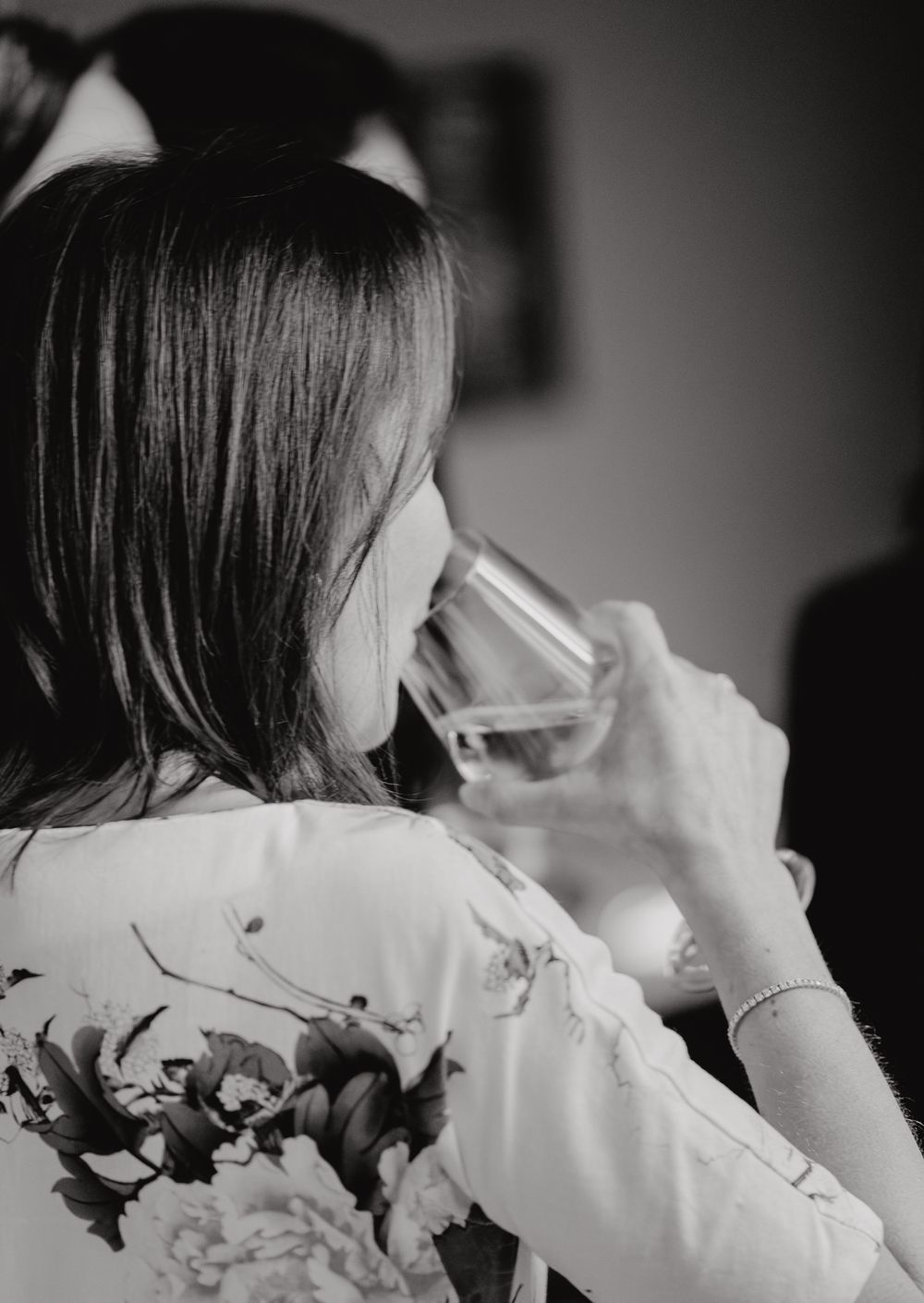A series of black and white images showing someone holding up and drinking from a glass against a dark background.