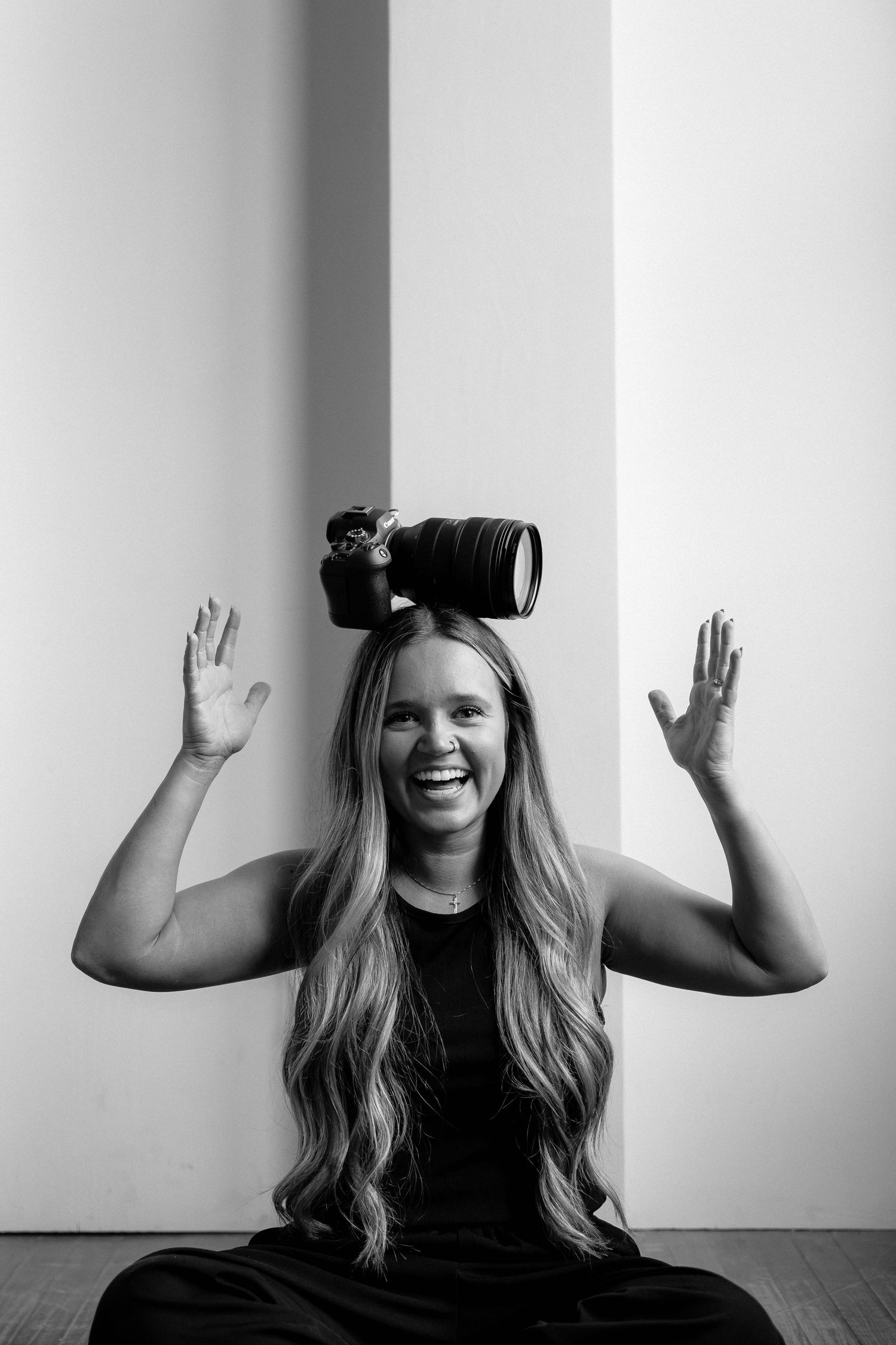 A playful monochromatic series showing someone with long hair balancing a VR headset and raising their arms expressively.