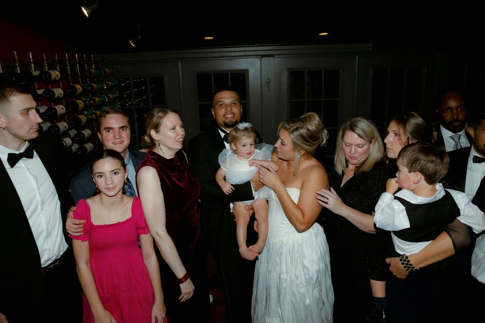 People dancing and socializing at a dimly lit party or reception venue.