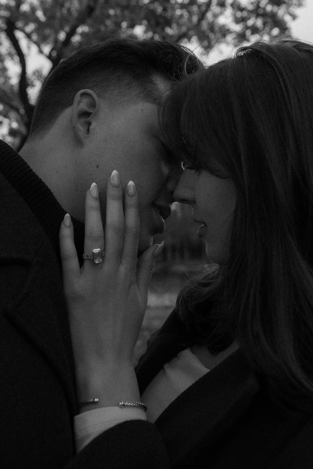 A romantic black and white photo showing an intimate moment with a hand displaying an engagement ring.