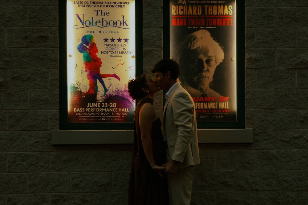 A row of movie posters and book covers displayed on a dark wall in a dimly lit room.