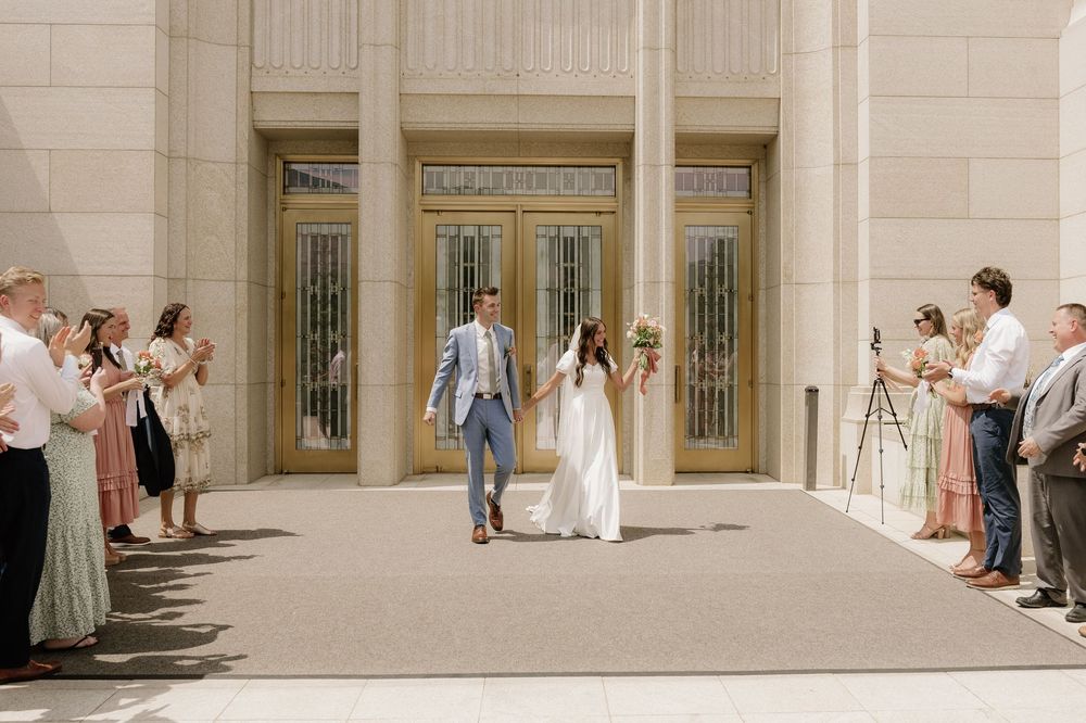 Wedding guests line up outside elegant doors to celebrate a couple's exit.