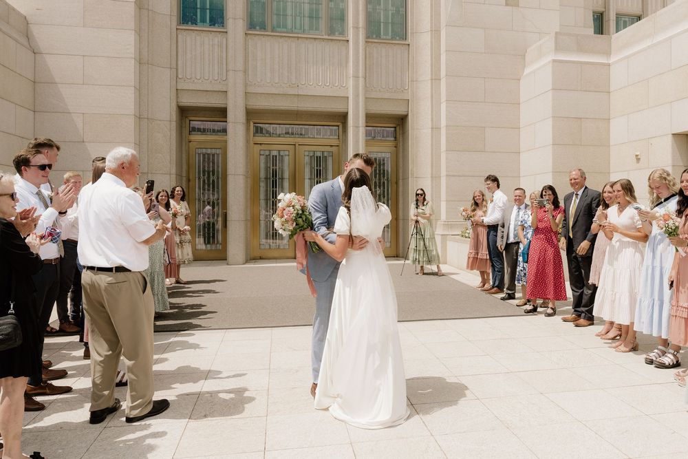 Wedding ceremony exit with guests clapping outside a grand building.