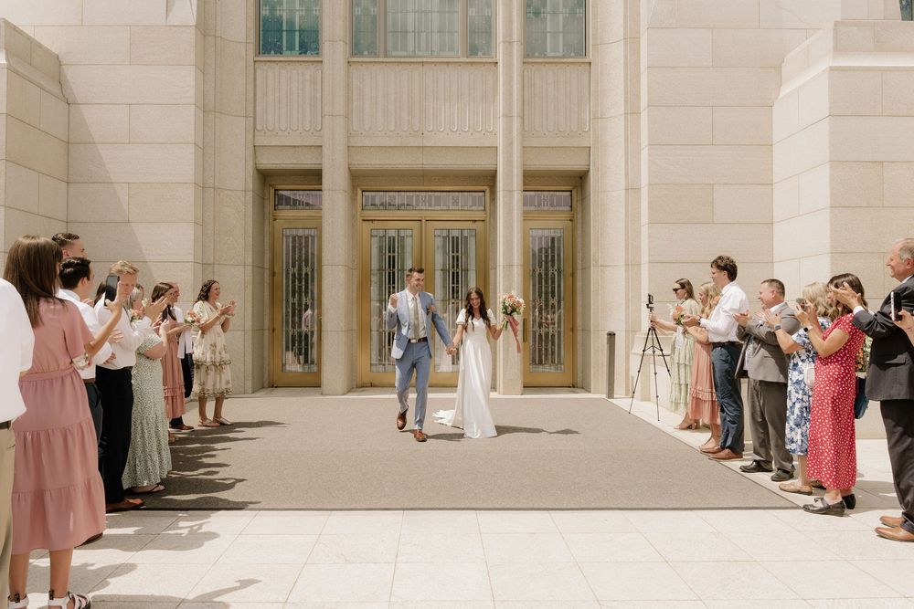 Wedding ceremony exit with guests lining the walkway outside a grand building.