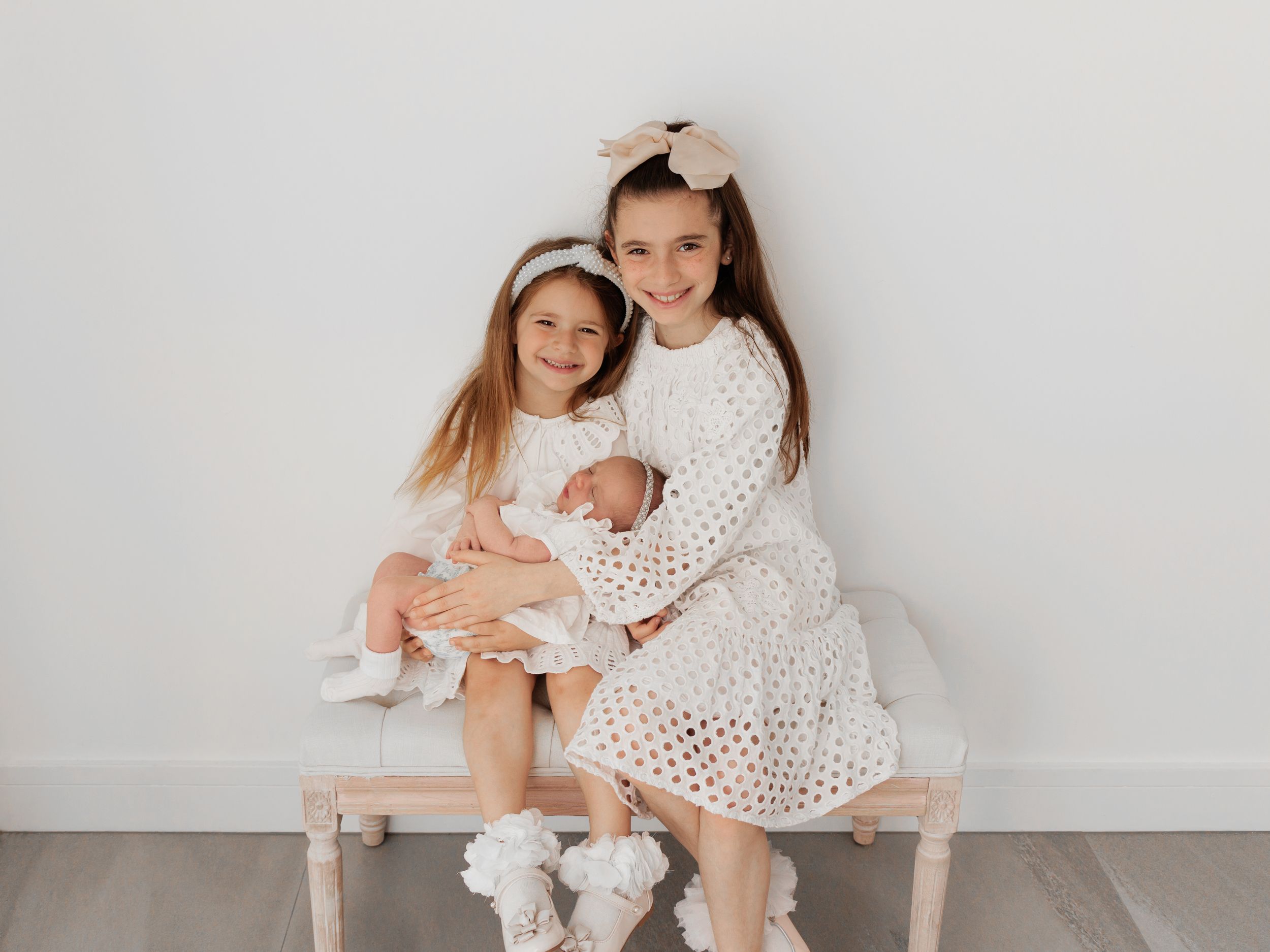 A series of monochromatic family photos showing intimate moments between mother and baby in matching white outfits.