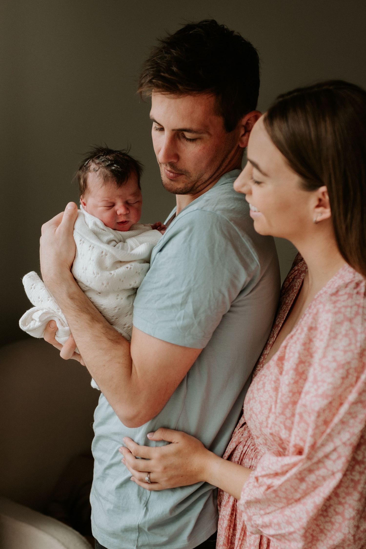 A family shares a tender moment together while comforting a crying baby.