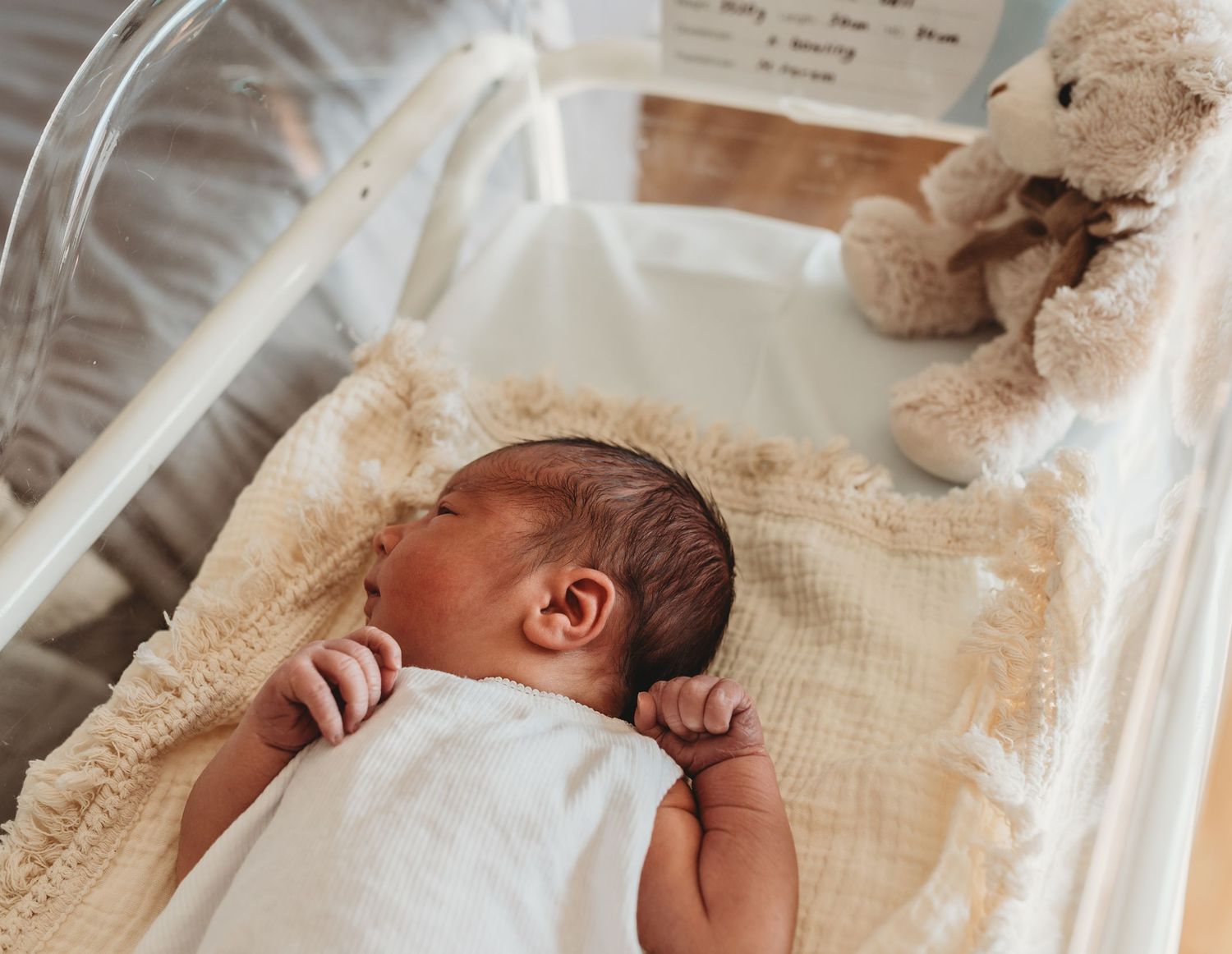 Newborn baby resting peacefully in a hospital bassinet.