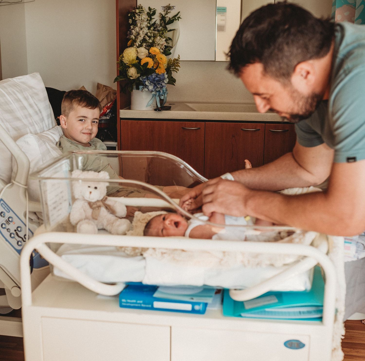 Medical staff examining a newborn baby in a hospital bassinet.