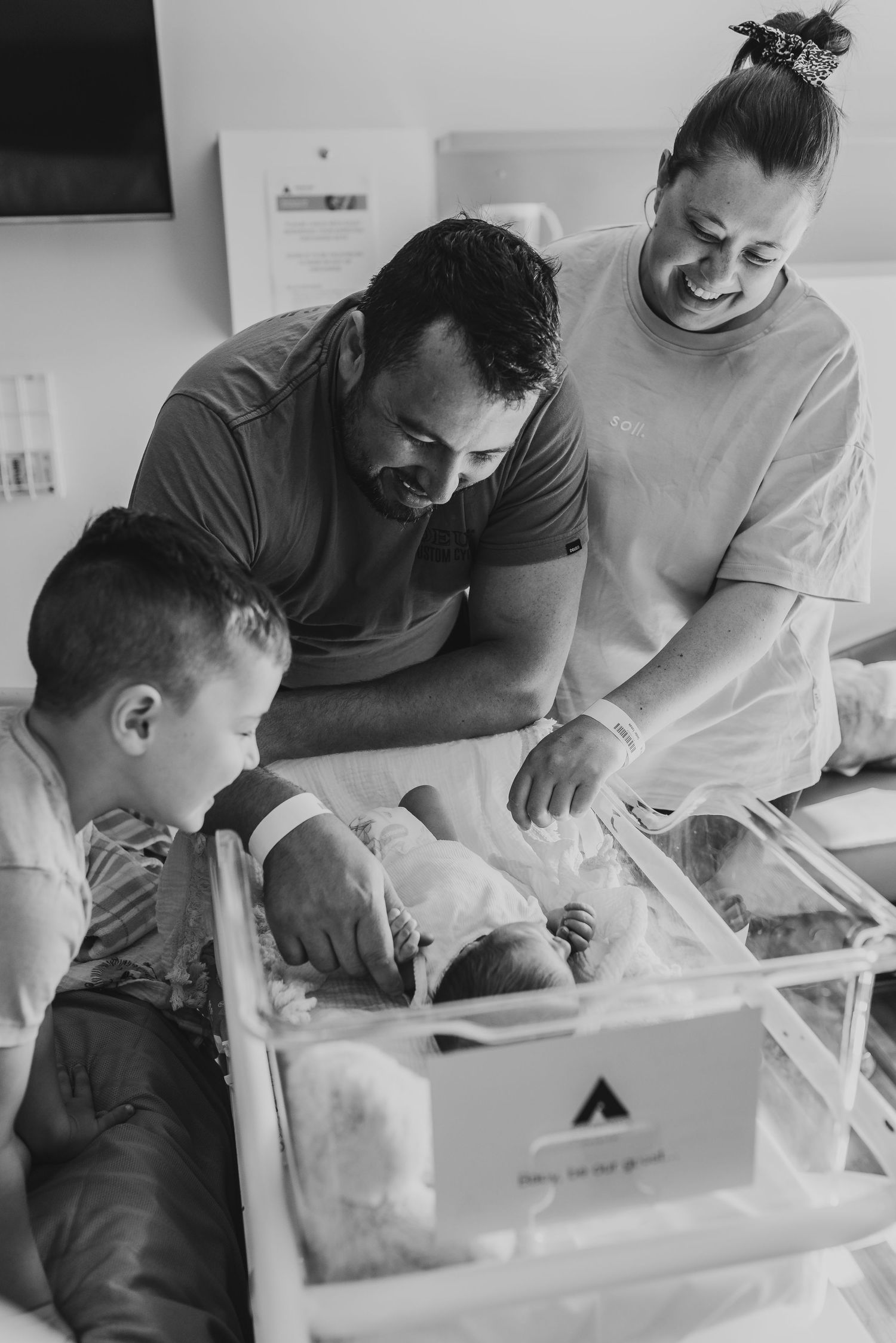 Family gathered around hospital bassinet to welcome their new baby.