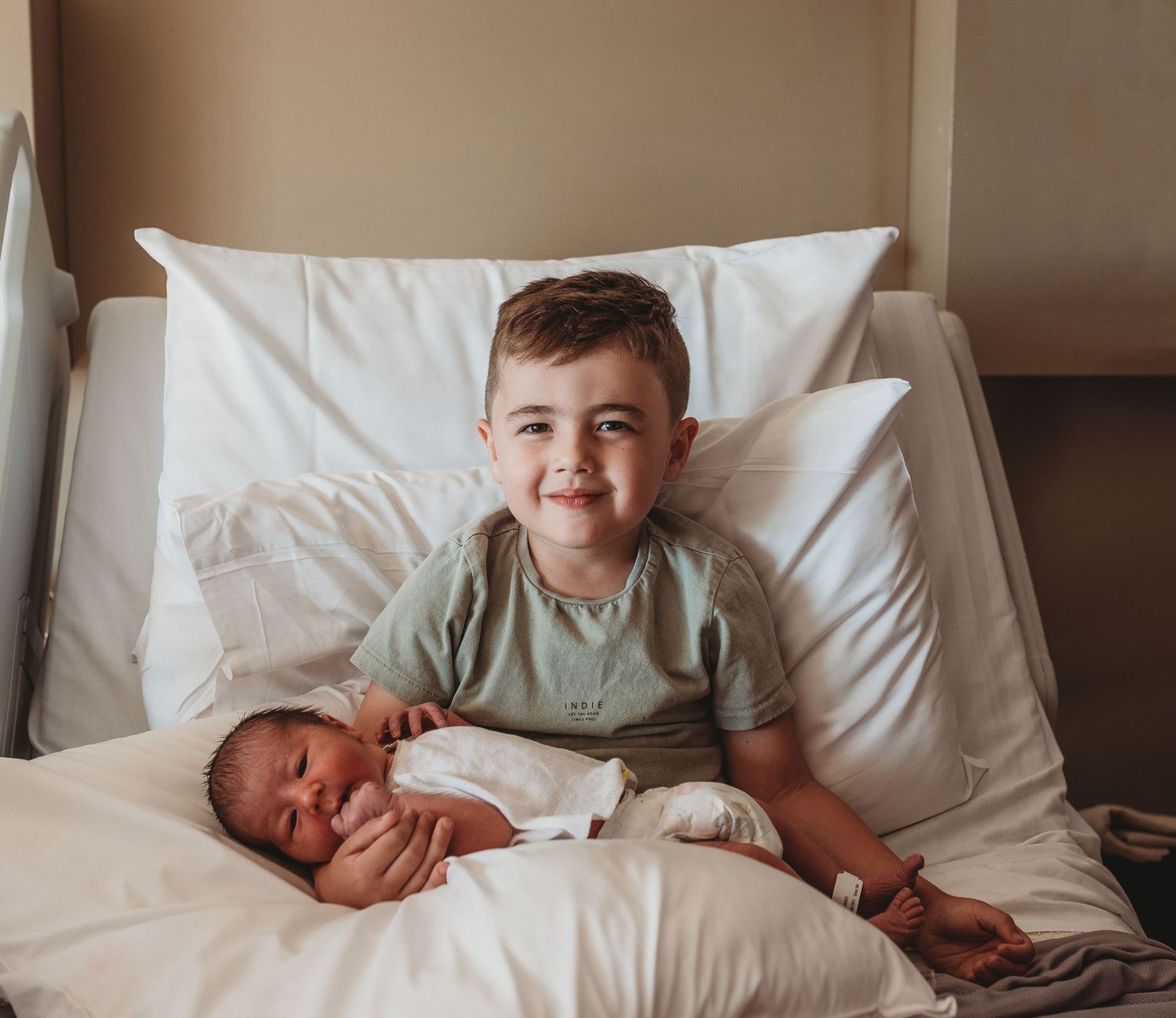A tender family moment captured on white bedding showing affectionate interactions with a newborn baby.
