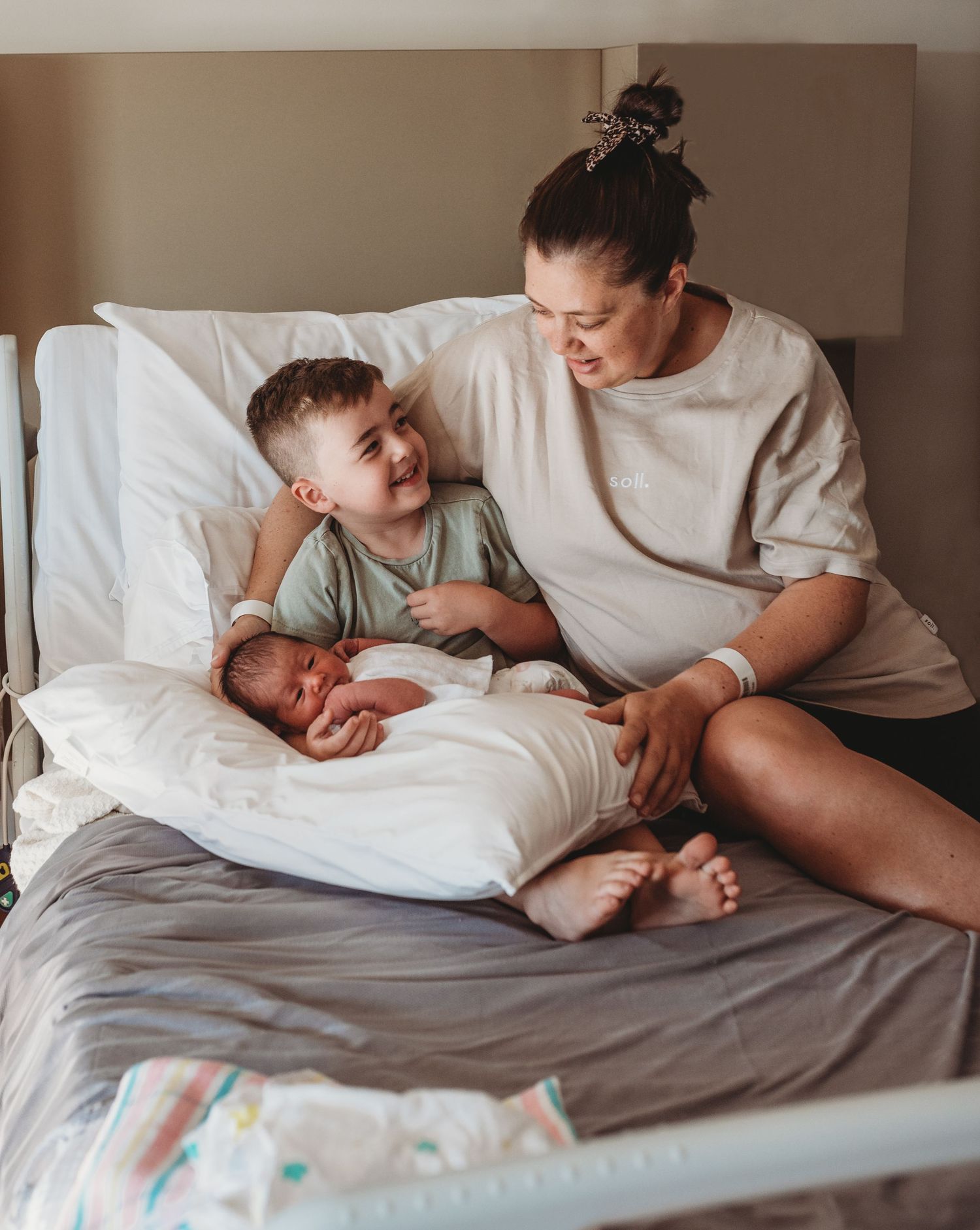 Family members sharing intimate bonding time together on a bed with white linens.
