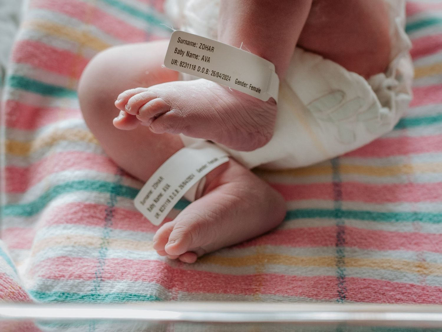 Close-up shots of newborn feet and hospital identification tags on striped bedding.