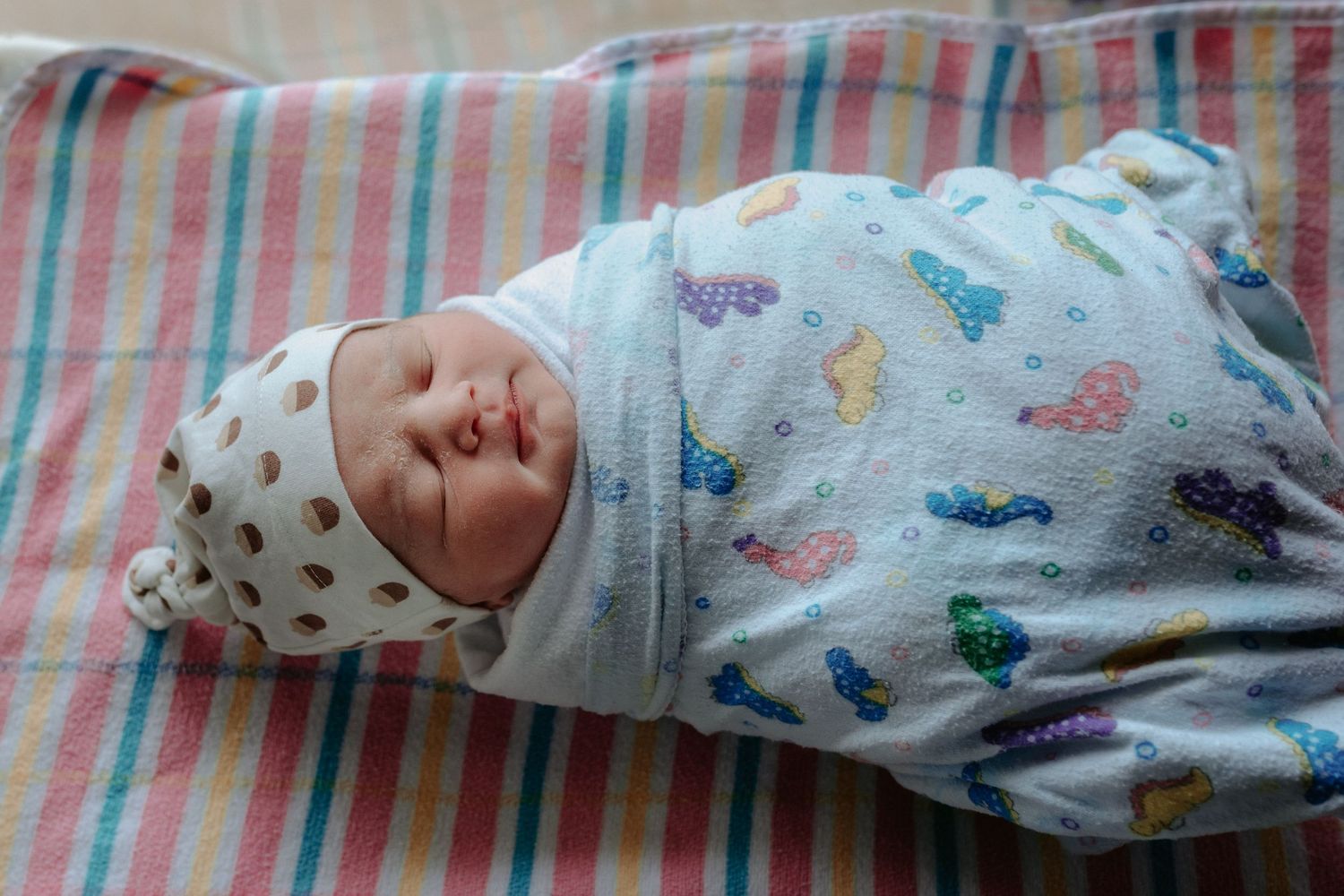 Newborn baby details on striped hospital bedding showing tiny features and medical tags.