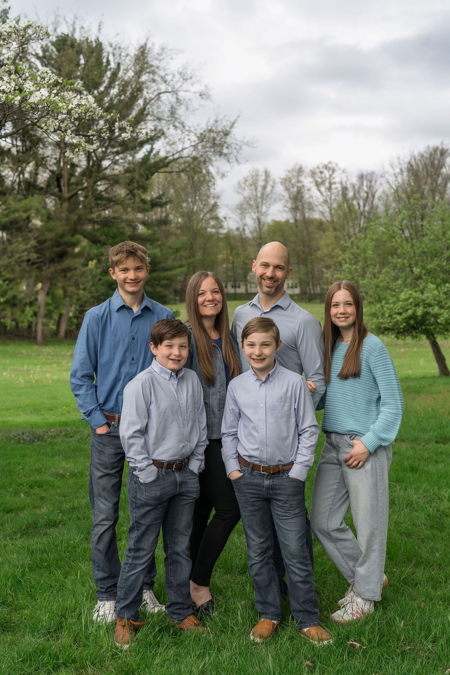 A group stands together outdoors in coordinated casual attire on green grass with trees in the background at a home in Stow, Ohio