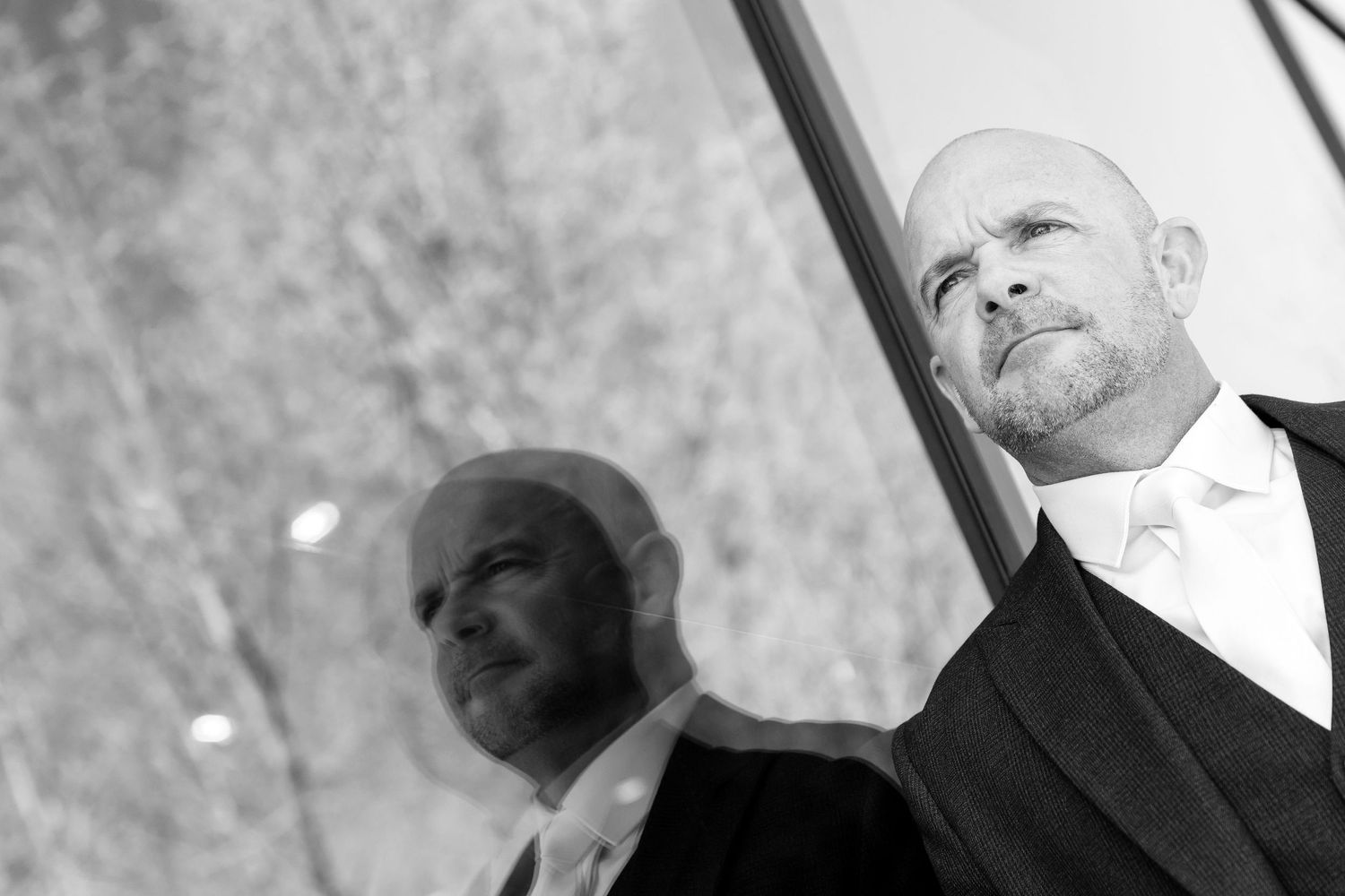 Groom captured with a reflective glass portrait before the ceremony at The Village Hotel.