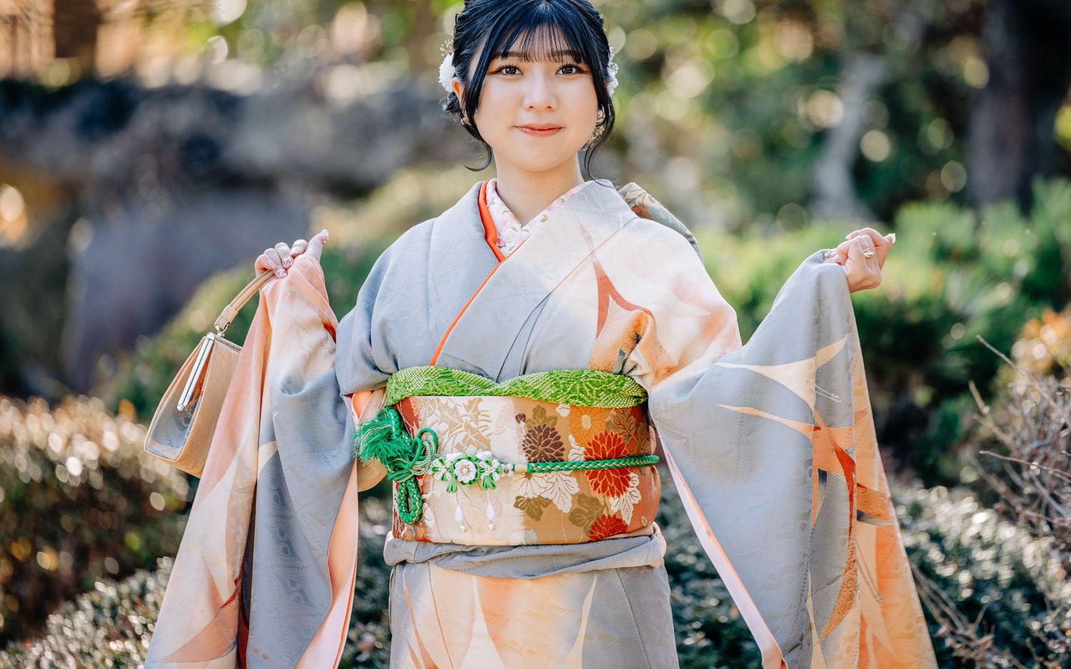 A girl in traditional Japanese kimono holding shopping bags in a garden setting.