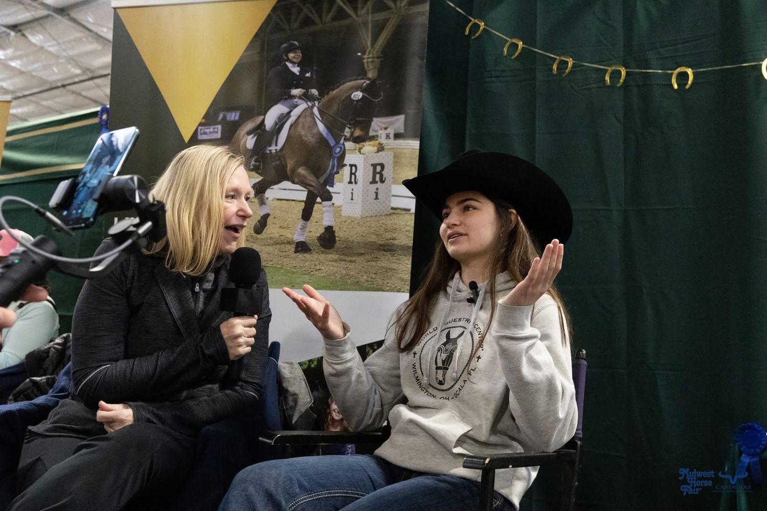 Two people chatting during rodeo event with decorative lights in background. Wisconsin Pro Rodeo PRCA Rodeo Photographer Dakota Cardenas