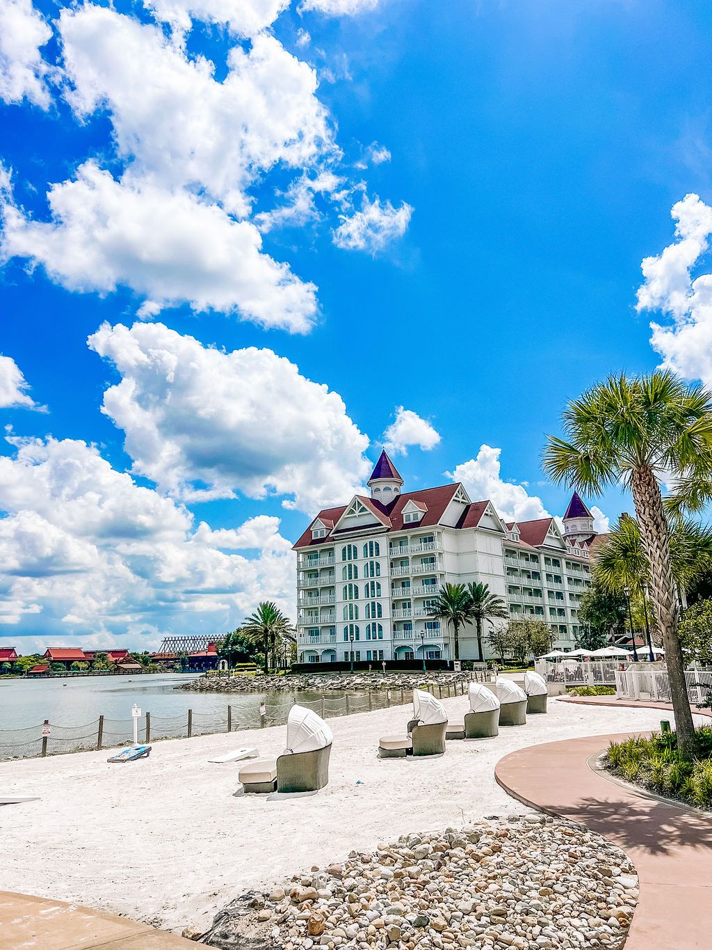 Panoramic view of a beachfront resort with white buildings and palm trees under blue skies.