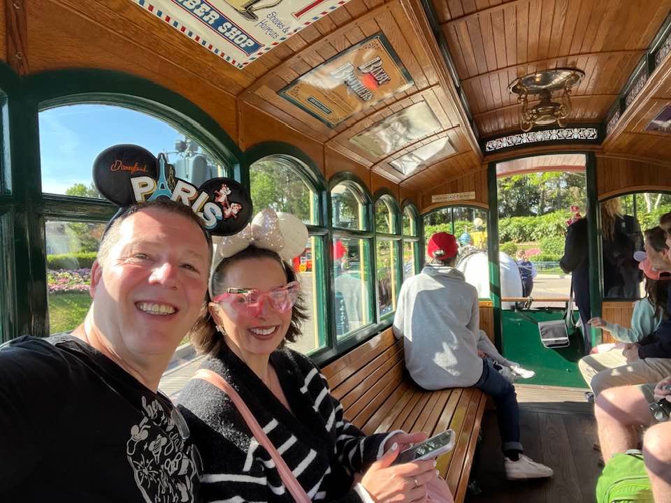 Passengers enjoy a scenic ride inside a vintage trolley car with wooden benches and ornate ceiling details.