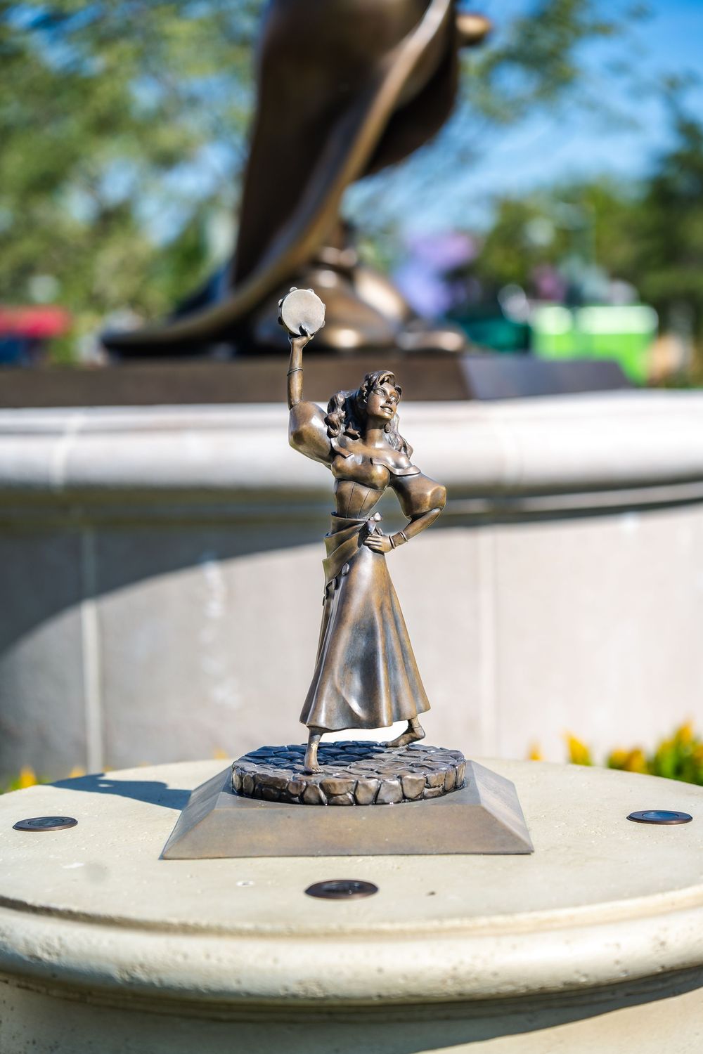 Close-up shot of a small silver figurine statue on a white pedestal showing a person holding something above their head.