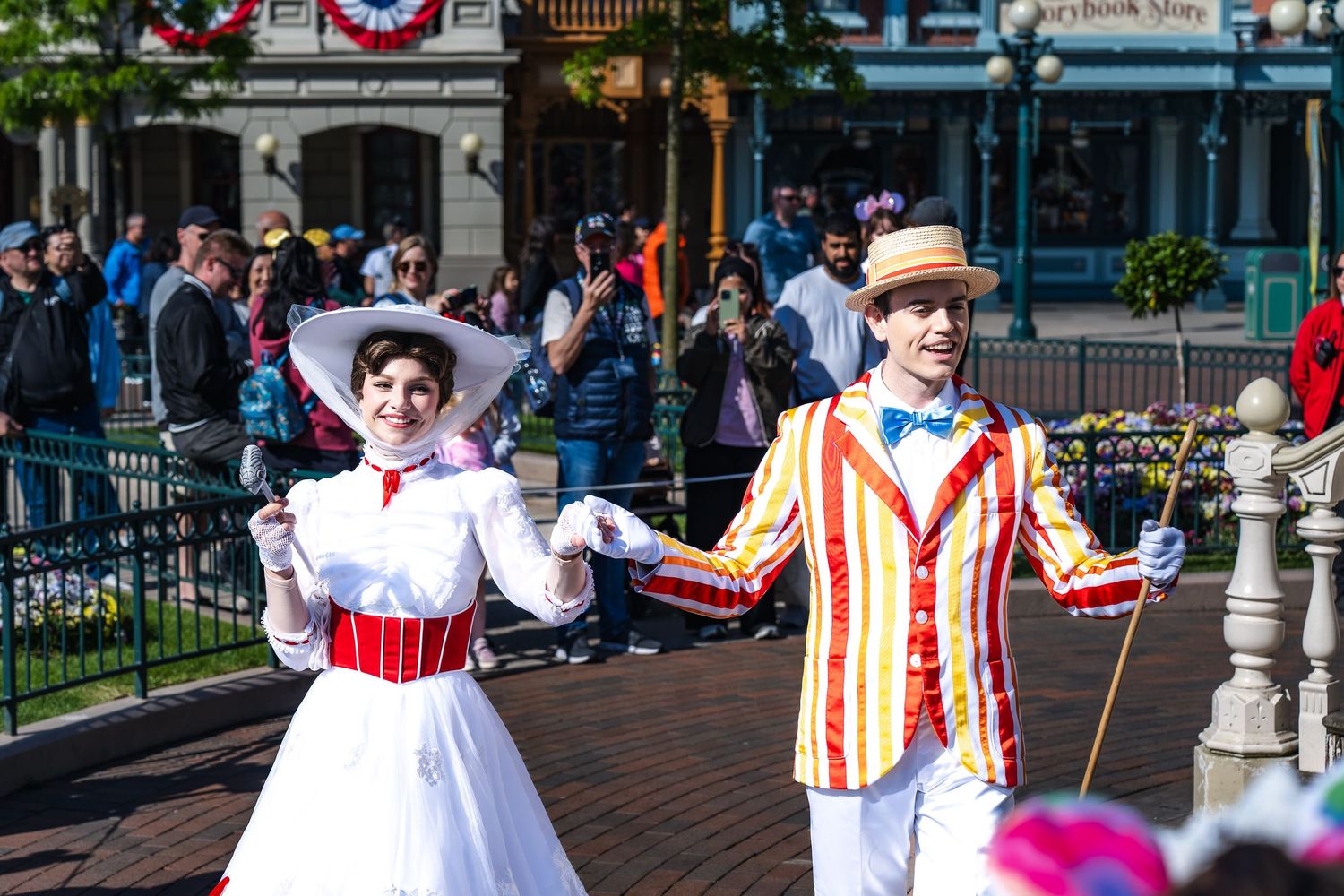 Performers in colorful vintage costumes dance and entertain visitors on Main Street at Disney theme park.