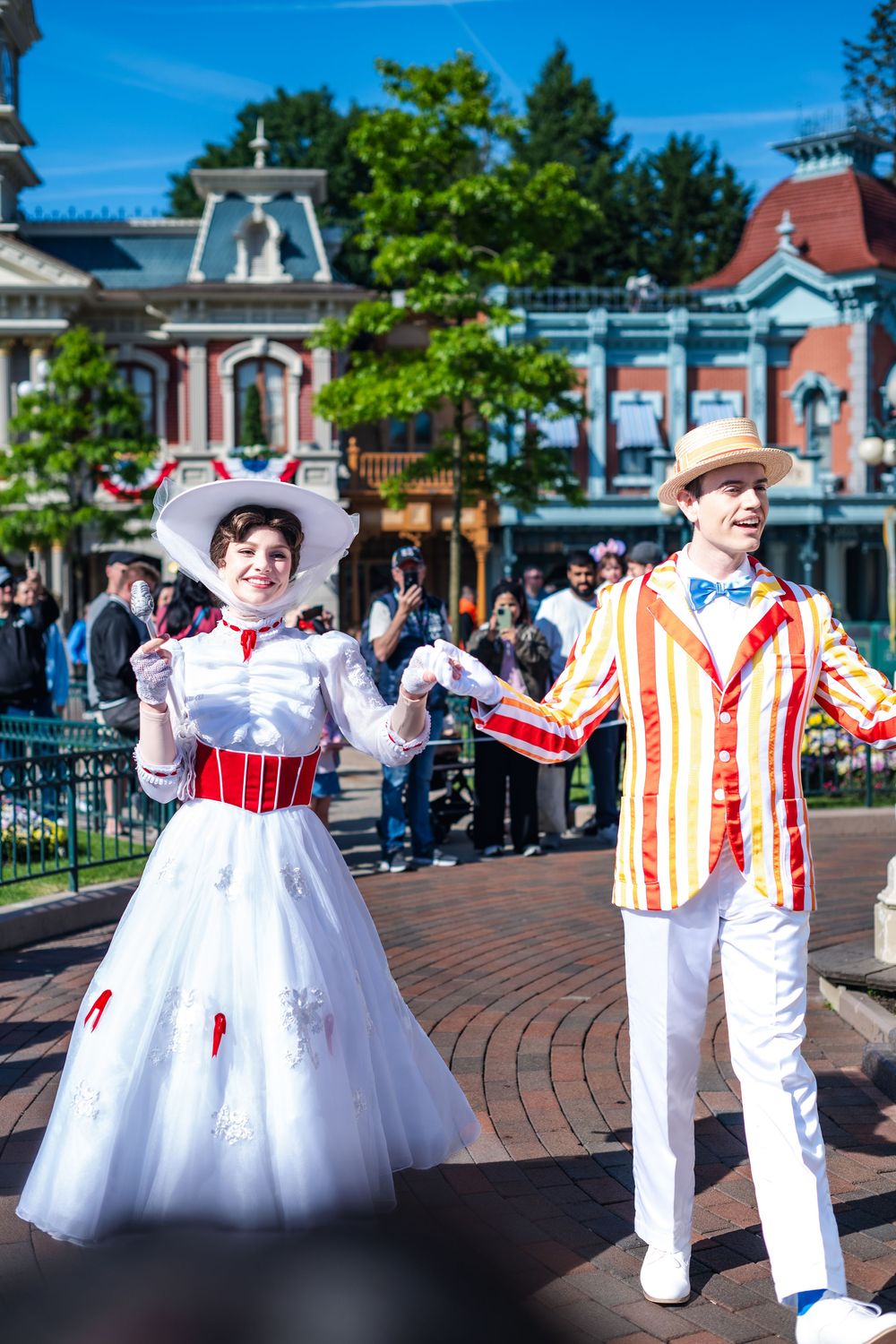 Costumed performers dressed as Mary Poppins and Bert entertain visitors on Main Street at Disneyland theme park.