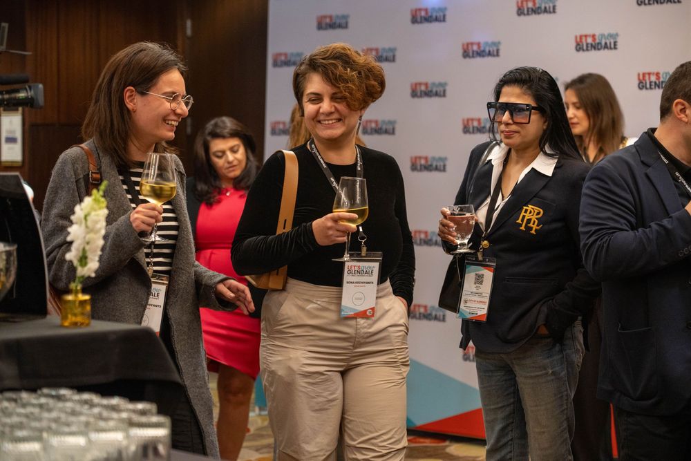 A group of people socialize and network while holding drinks at a professional business event.