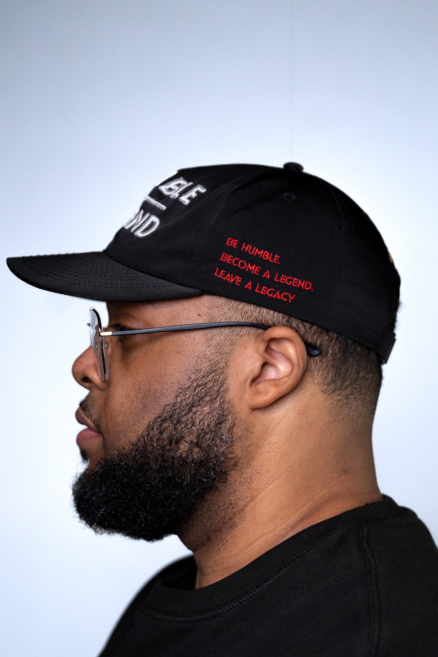 Side profile of a black baseball cap with red text and glasses.
