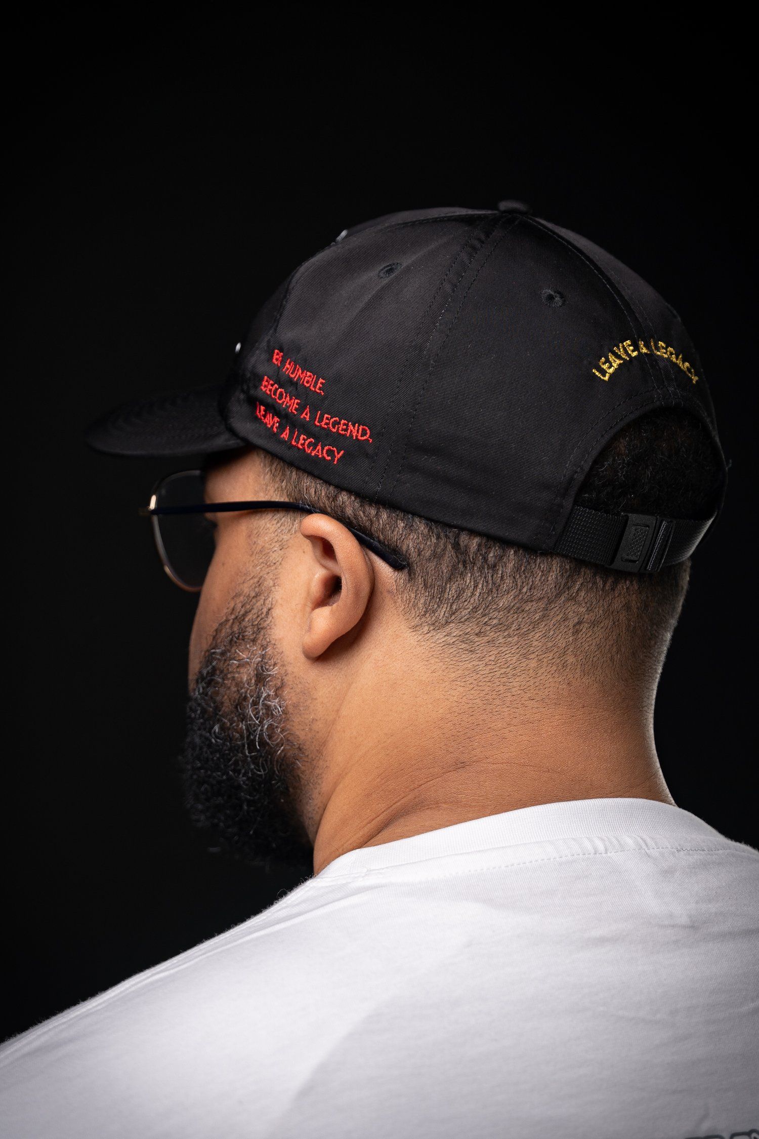 Close-up rear view of black baseball cap with red embroidered text.
