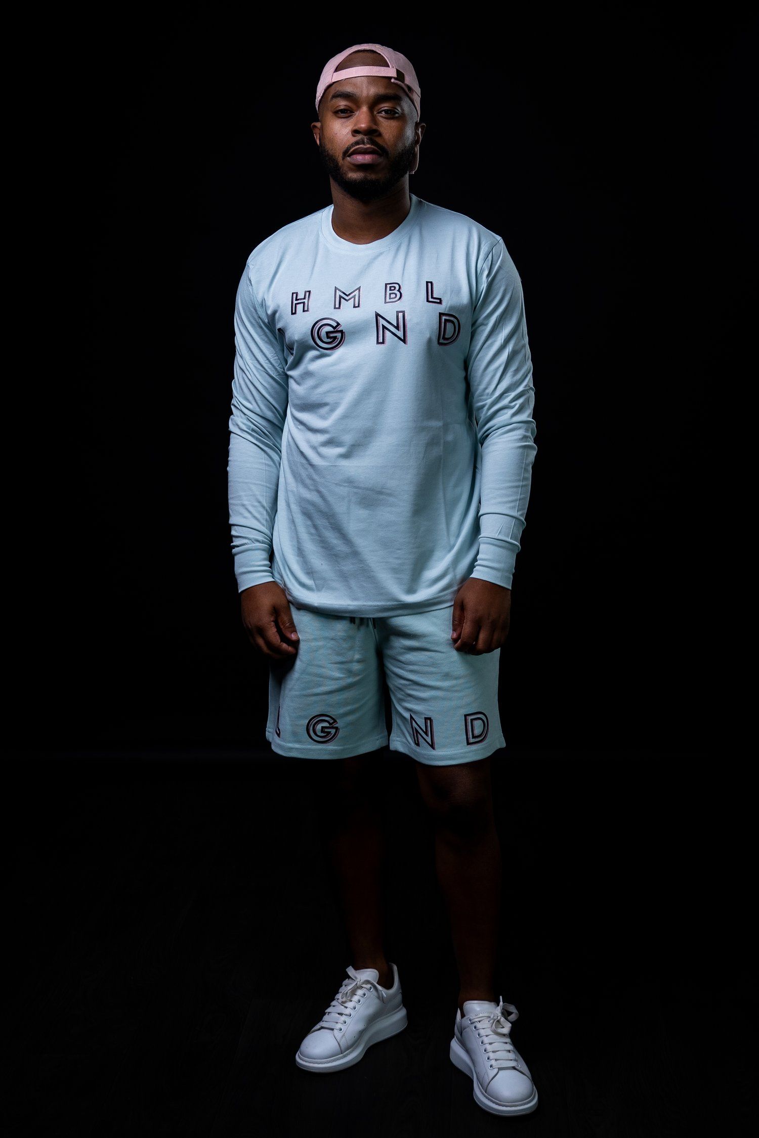 Full body shot of white athletic wear set with HMBL LGND branding against black backdrop.