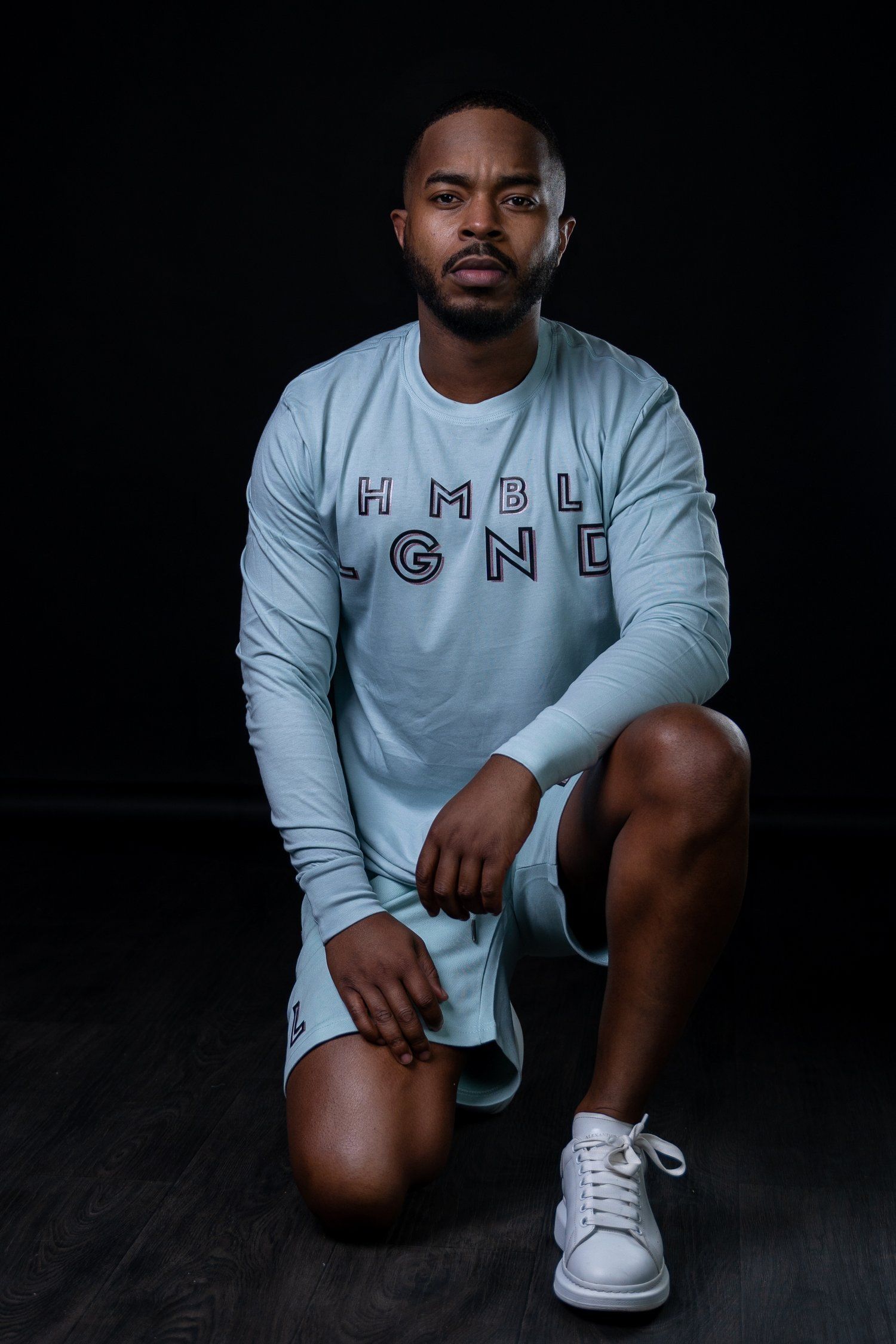 Athletic modeling pose showcasing white HMBL LGND branded loungewear set.