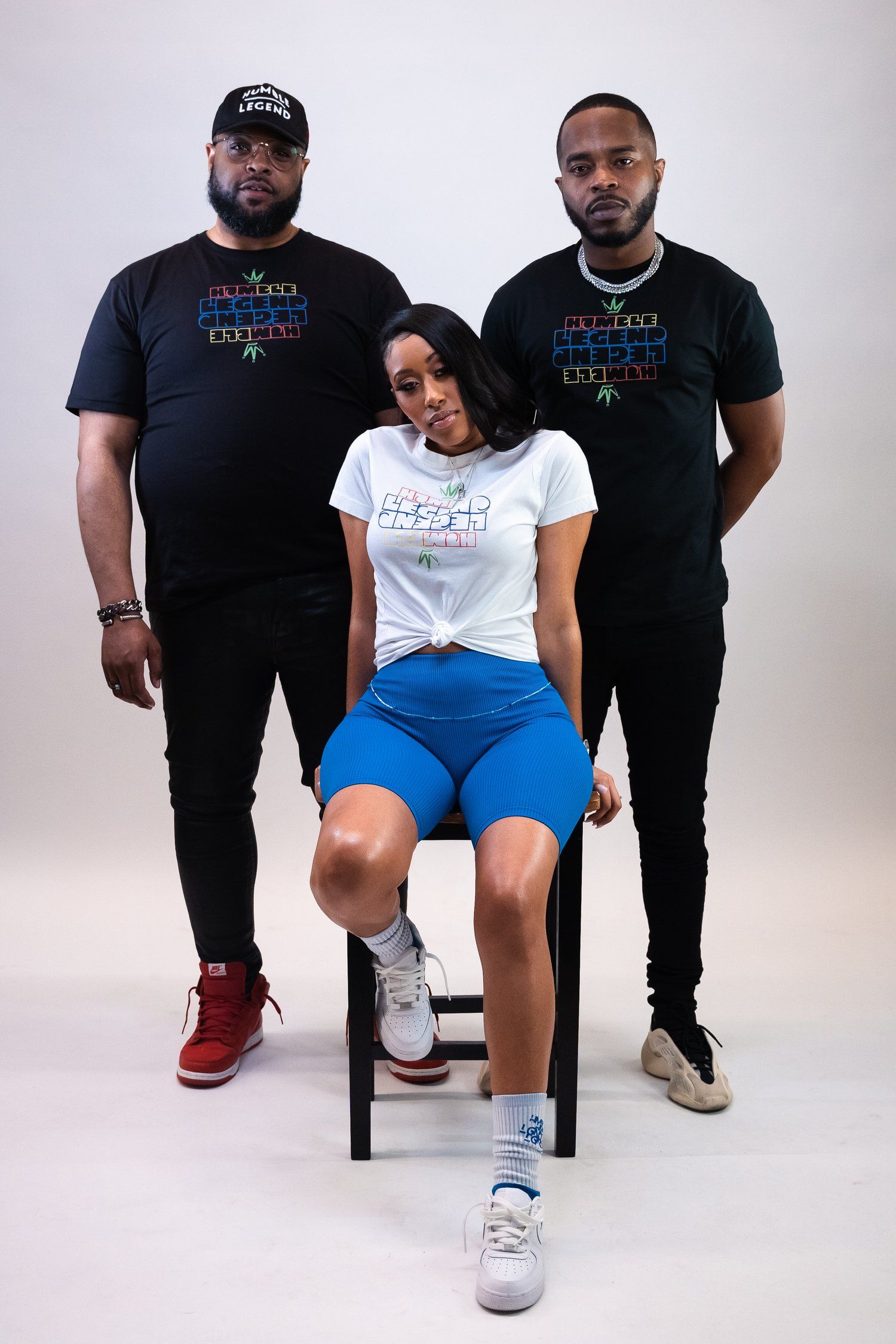 Three people posing in coordinated t-shirts and casual wear during a professional photoshoot.