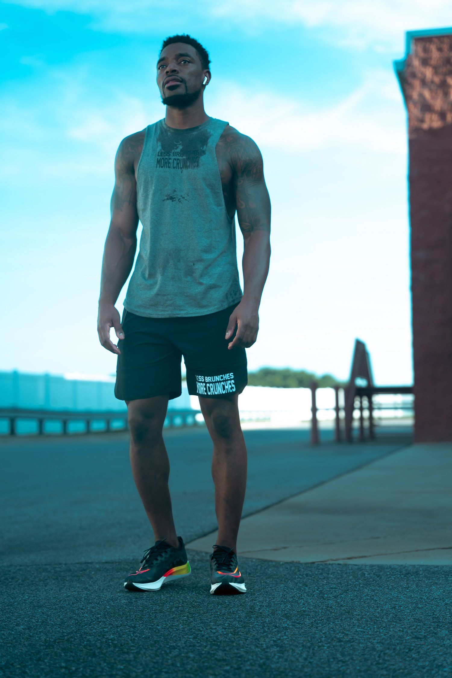 Athletic person in workout gear standing on a waterfront path during blue hour.