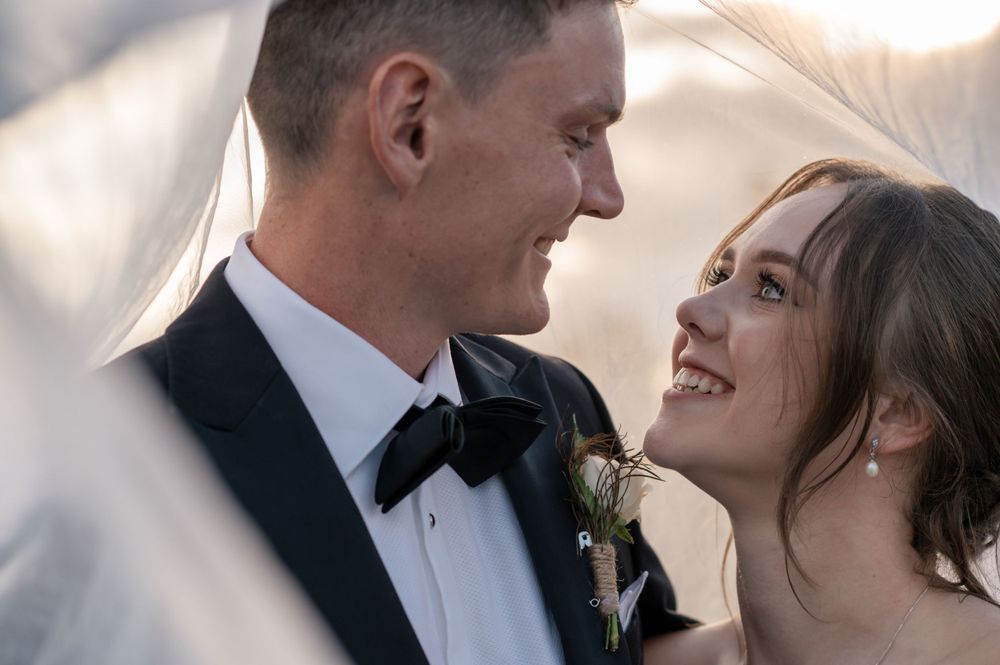 An intimate wedding portrait through flowing white veil fabric at sunset Cambridge New Zealand