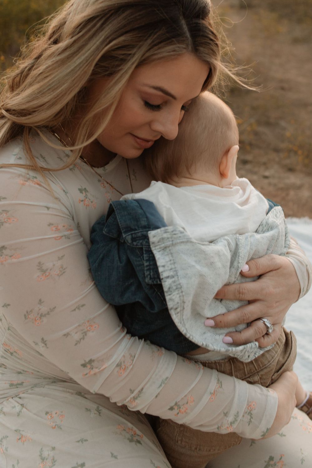 Intimate moment between mother and baby during outdoor photo session at sunset.
