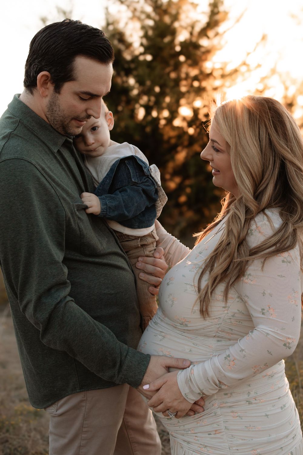 A family shares a tender outdoor moment at sunset while expecting a new addition.