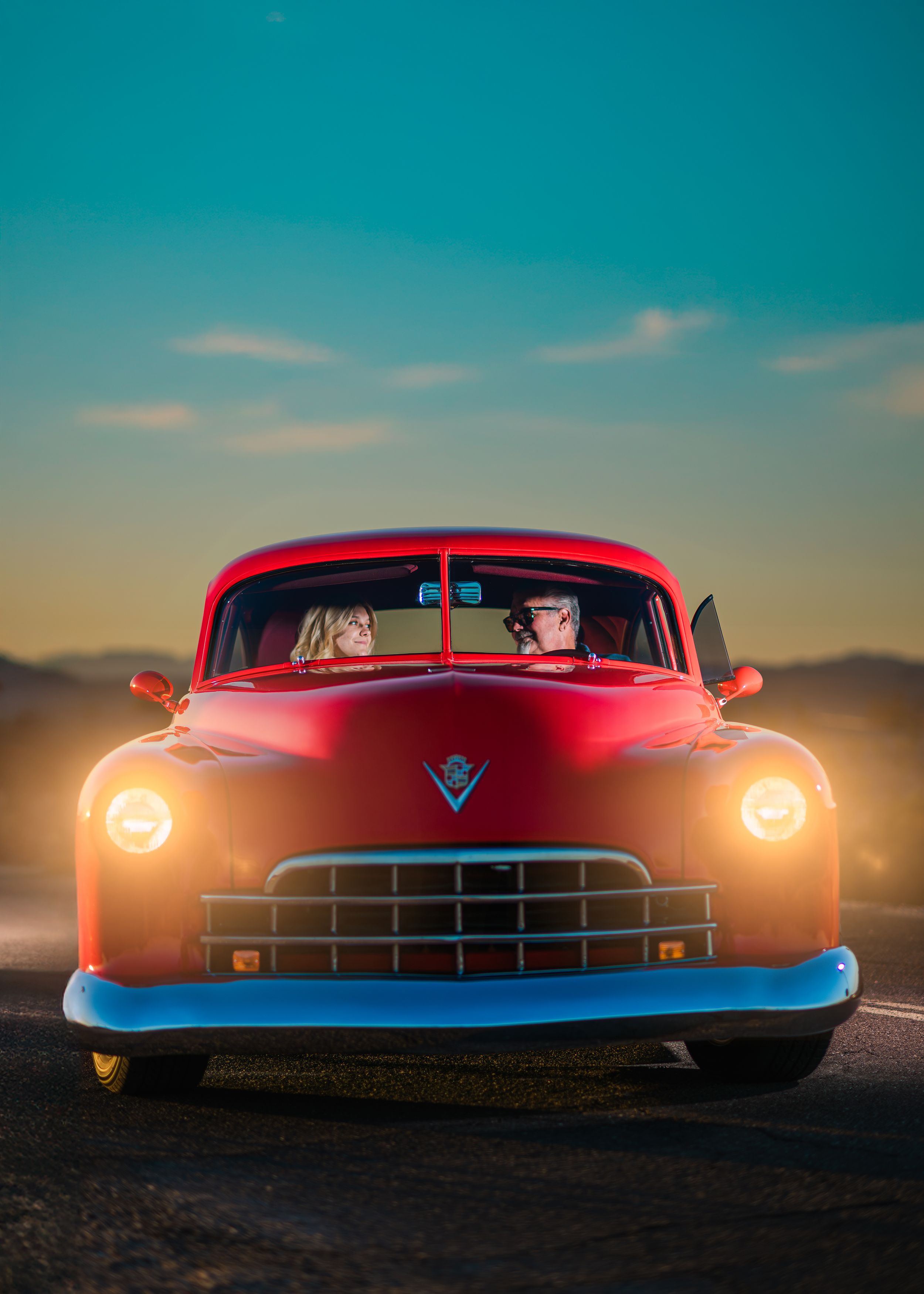 Create portrait of a father and daughter in a red hotrod at sunset. Create portrait photography by Dusty Wooddell.