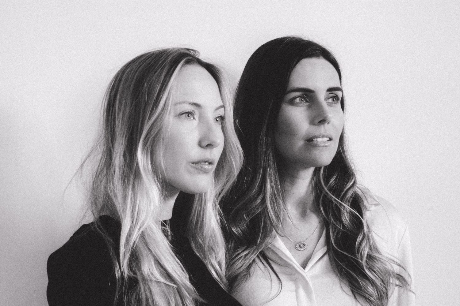 Black and white portrait series showing two models in close proximity against white backdrop.